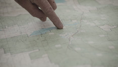 index finger of an old man tracing border line of western yellowstone on a paper map