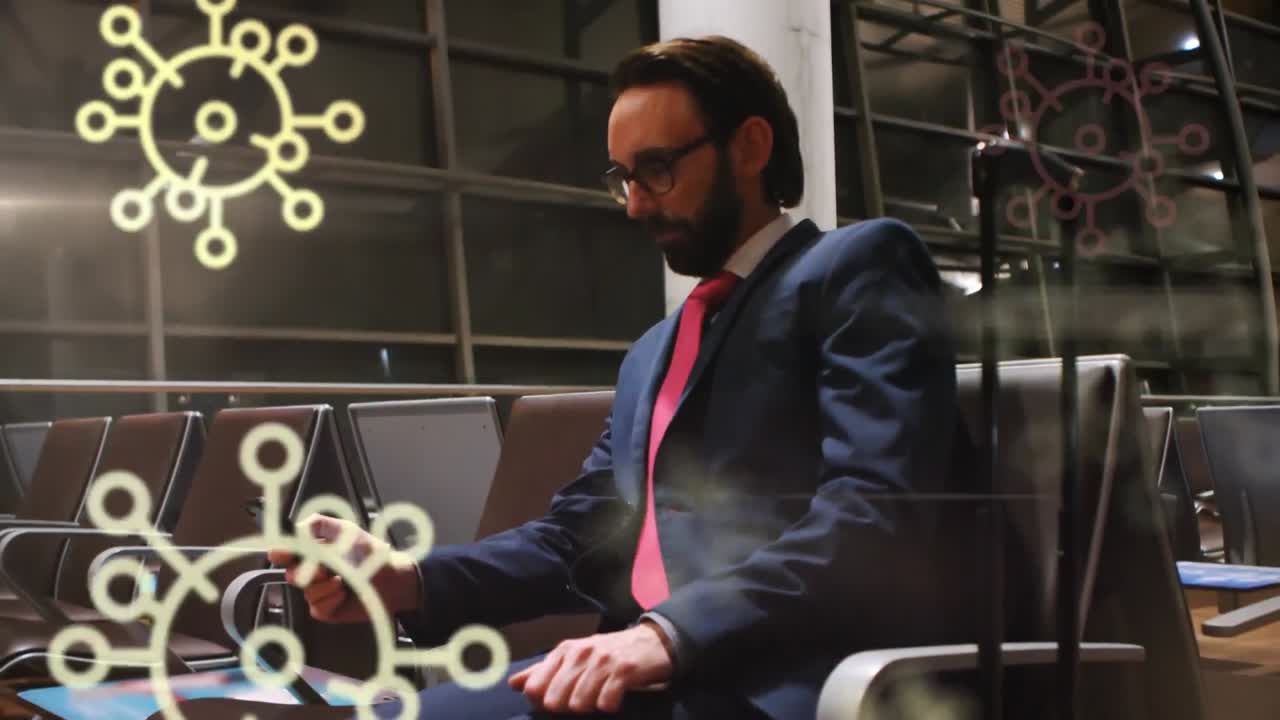 animación de iconos flotantes de células de covid-19 sobre un hombre de raza mixta que usa un teléfono inteligente en el aeropuerto