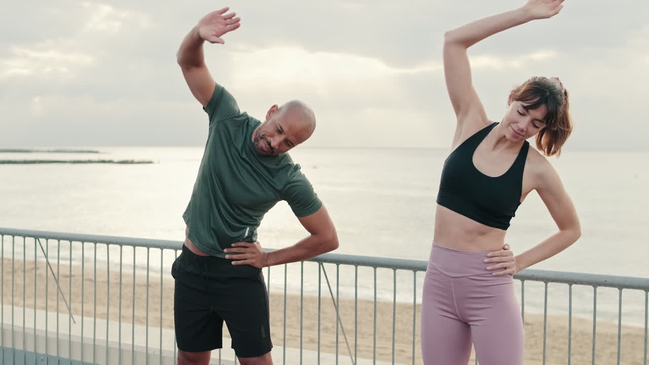 Healthy Couple Stretching on a Waterfront Promenade