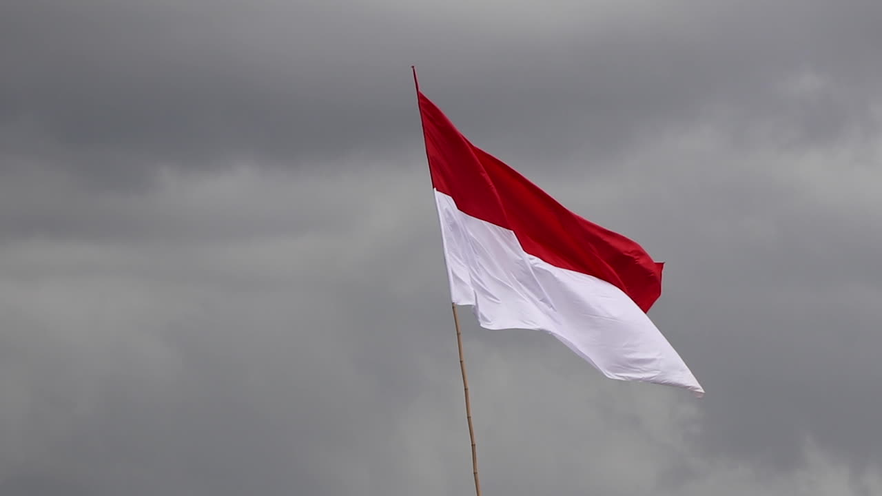 Merah Putih, Indonesian Flag fluttering in breeze against dark clouds