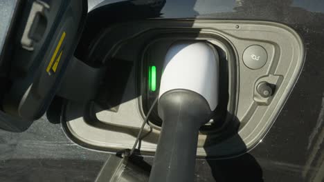 electric ev re- charge cable plugged into car socket close up shot