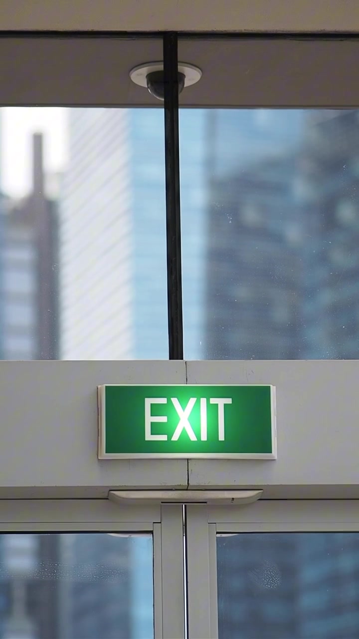 Illuminated Green Exit Sign Above Glass Doors in Modern Building
