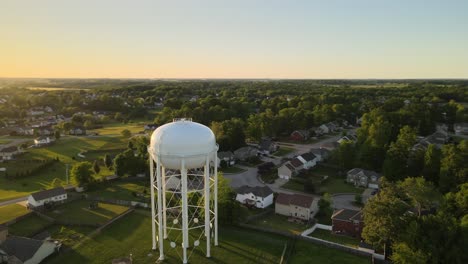 órbita-Aérea-De-Una-Torre-De-Agua-En-Los-Suburbios-De-Clarksville,-Tennessee,-Que-Revela-Una-Hermosa-Puesta-De-Sol-Al-Final