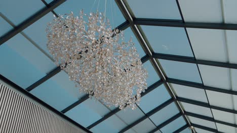 gran lámpara de techo de cristal suspendida en un espacio moderno con techo de vidrio