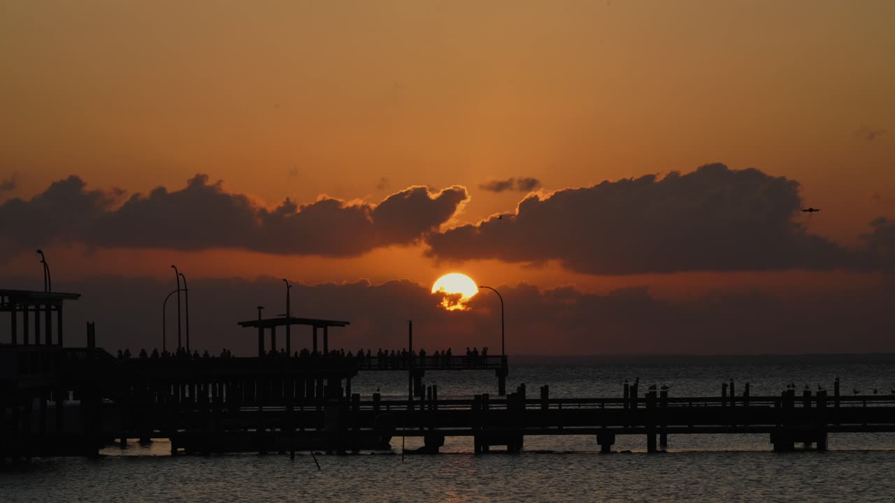 Sunset over a Pier with Silhouetted Figures