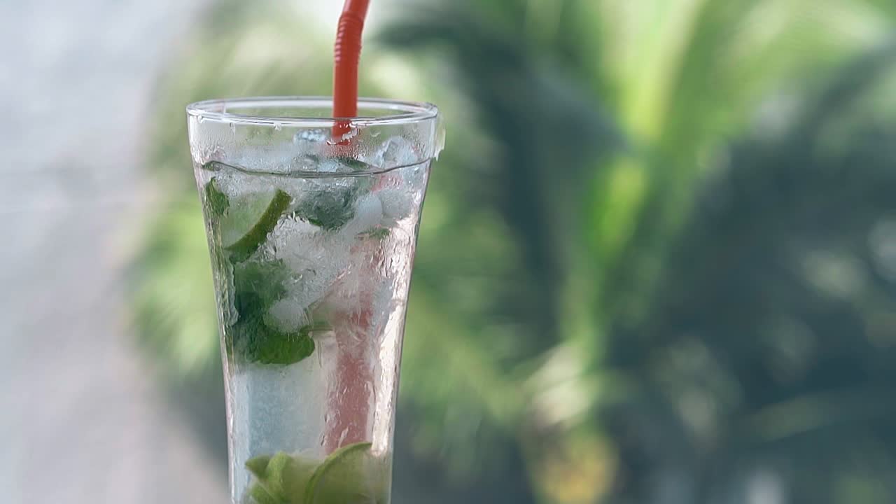 모지토가 흐릿한 손바닥에 서 있는 약간 얼어붙은 유리