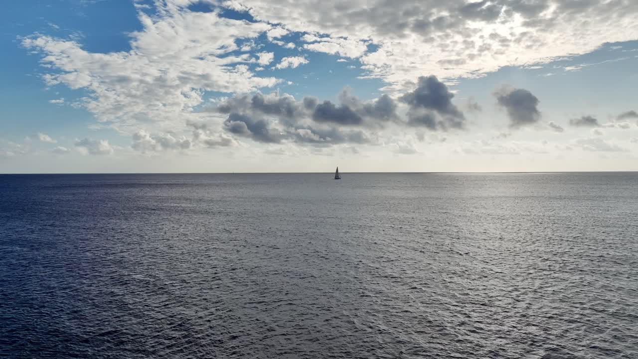 Drone shot of a little lonely sailboat out at sea daytime.