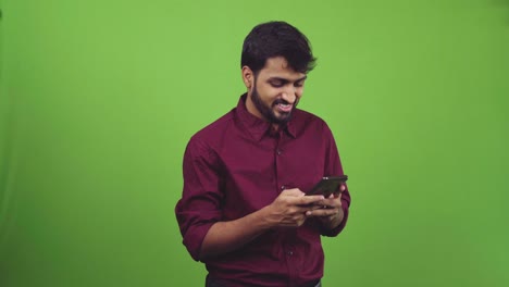 Asiatischer-Mann-In-Burgunderfarbenem-Hemd,-Lächelnd-Und-SMS-In-Einem-Green-Screen-Shooting