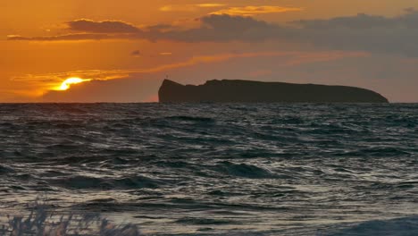 amanecer sobre la isla con olas tormentosas