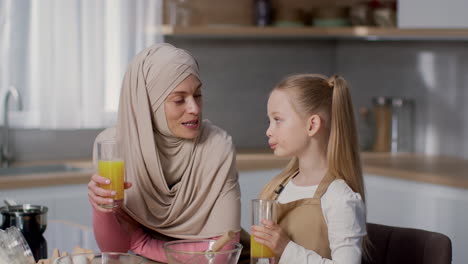 mother and daughter enjoying orange juice in the kitchen