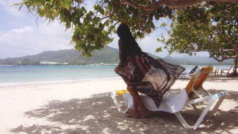 brisa marina flotando en su ropa de playa mientras la dama latina regresa a la fresca sombra de los árboles para descansar