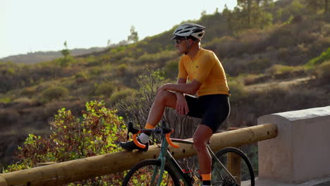 el ciclista se relaja después de llegar, disfrutando de la magnífica vista de la montaña delante de él