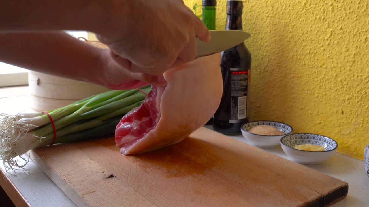 manos masculinas cortando la piel de la panceta de cerdo en la cocina casera