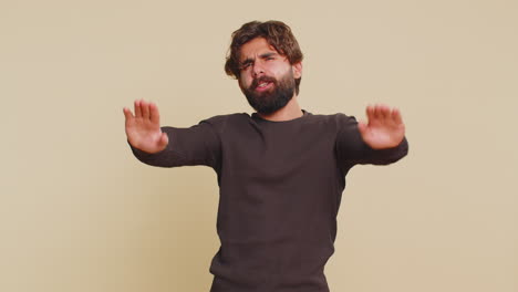 frustrated annoyed irritated lebanese man covering ears gesturing no against beige background
