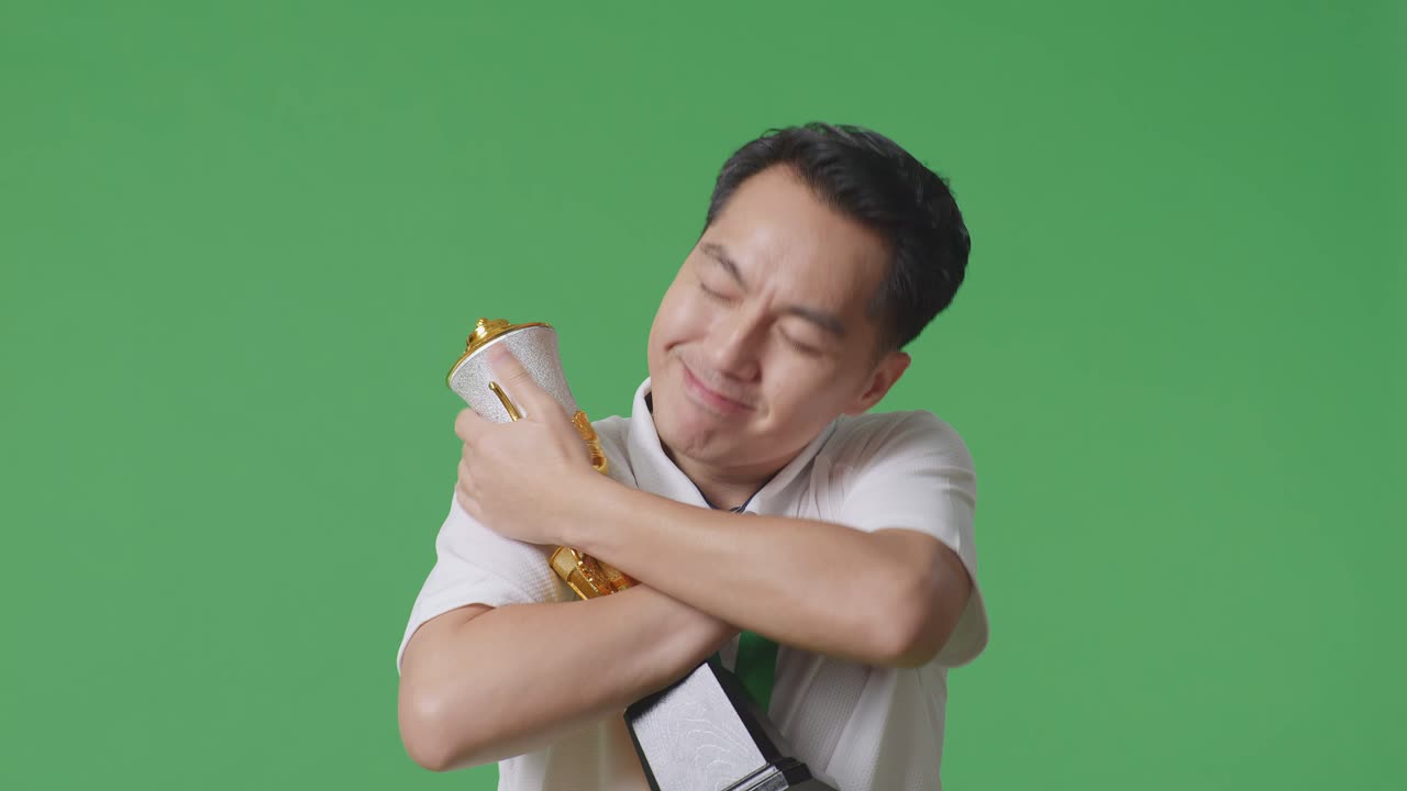 금메달을  아시아 남자가 황금 트로피를 안고 자랑스럽게 첫 번째 우승자로 우승하는 녹색 스크린 배경에서 스튜디오에서