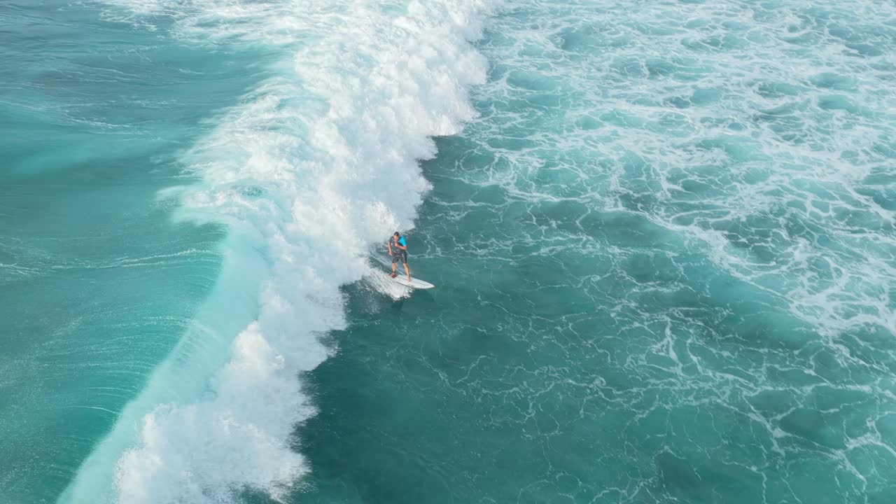 Vista aerea con drone di un surfista che cavalca una grande onda oceanica turchese a Bali