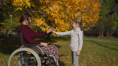 smiling preschooler daughter gives mother yellow leaves