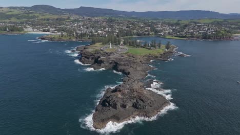 drone orbits right above kiama nsw australia lighthouse with rocky exposed point establishing the quaint summer destination