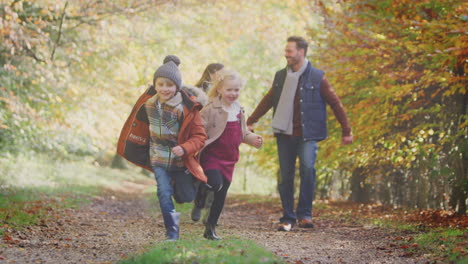 family walking along track in autumn countryside with children running ahead