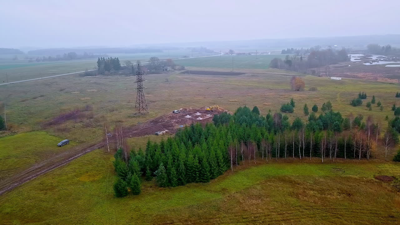 árboles coníferos verdes cerca del sitio de construcción de la torre de transmisión en el campo