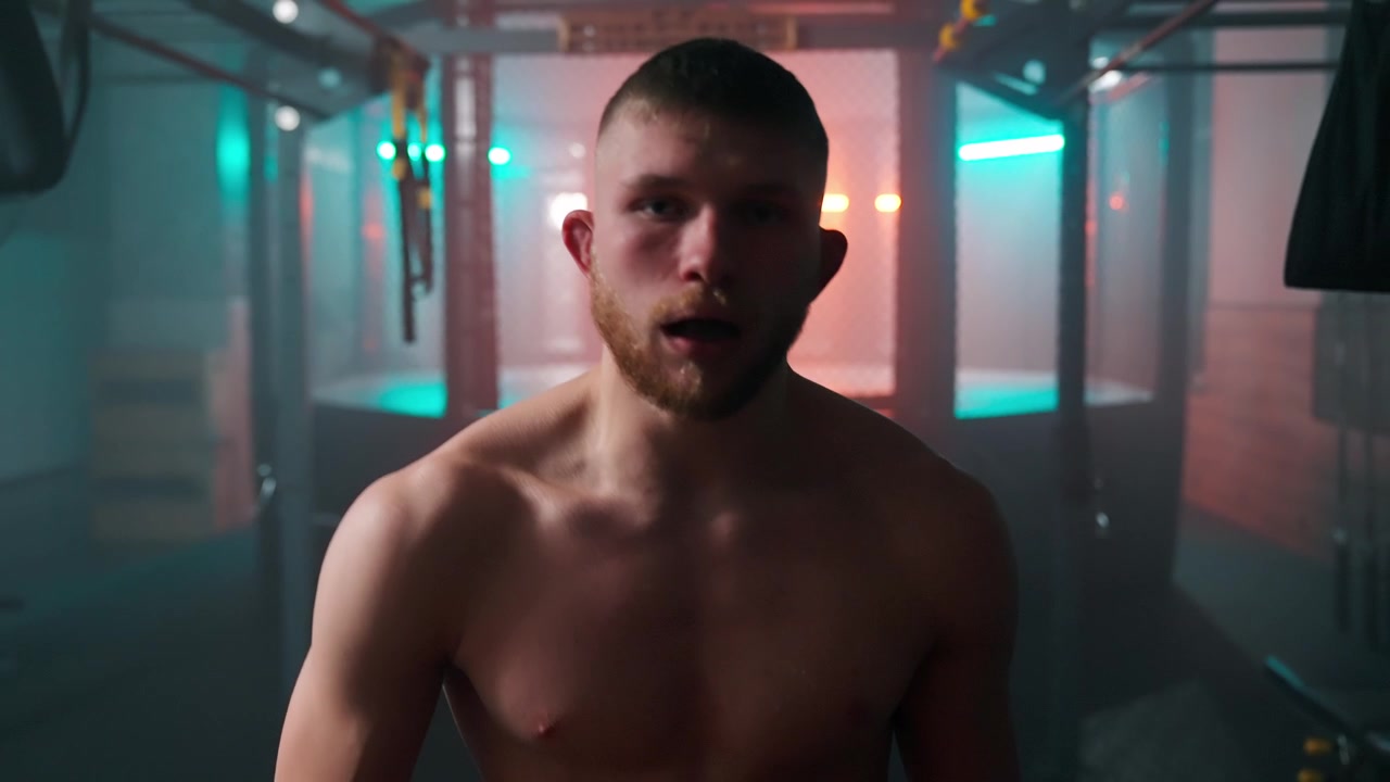 Uomo muscoloso che respira affannosamente in una palestra con illuminazione drammatica