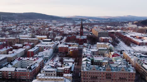 Aerial-circling-panoramic-view-of-Sundsvall-snowcapped-city-in-Sweden-with-Gustav-Adolfs-church-and-bell-tower-in-background