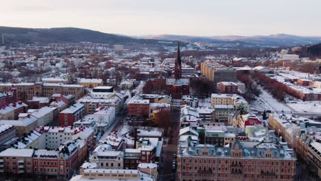 aerial circling panoramic view of sundsvall snowcapped city in sweden with gustav adolfs church and bell tower in background