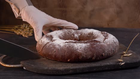 the chef cuts homemade sourdough bread loaf into slices with kitchen knife