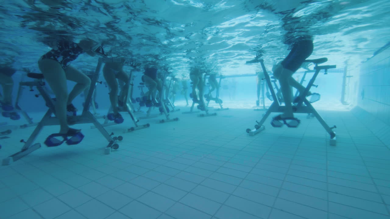 vista submarina de personas en bicicleta acuática en una piscina en cámara lenta