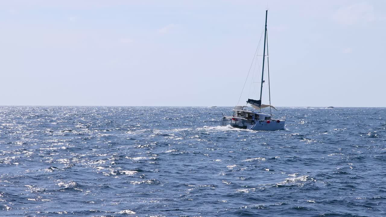 태국 푸켓 근처의 바다를 가로질러 조용히 항해하는 요트, 밝은 낮빛 아래, 평온한 해양 아름다움을 포착합니다.