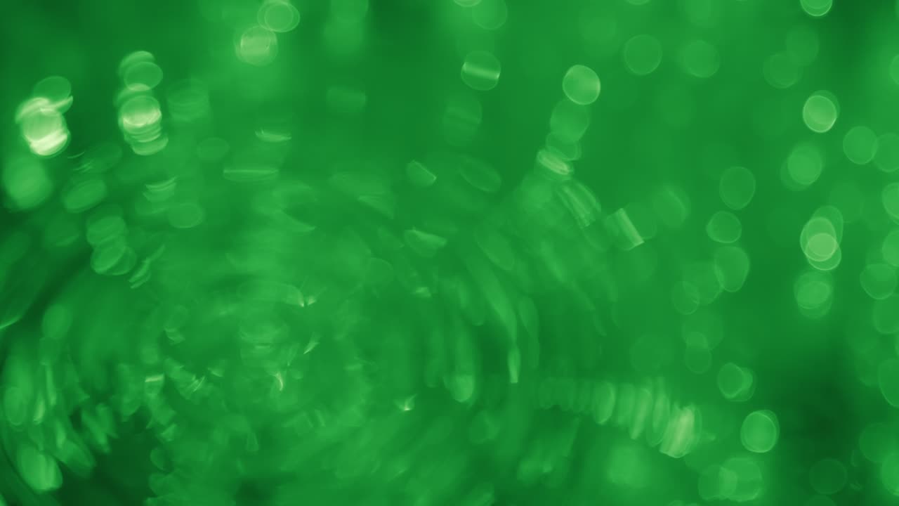 Rain drop falling into water, reflection in water bokeh of green lights. Blurred bokeh.