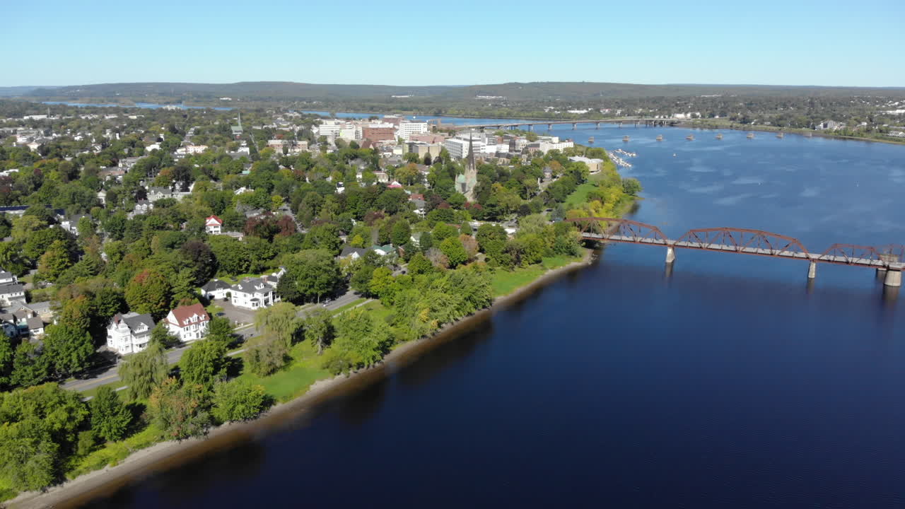 AERIAL: Flying Over The Saint John River Toward Downtown Fredericton. Walking Bridge In The Foreground.