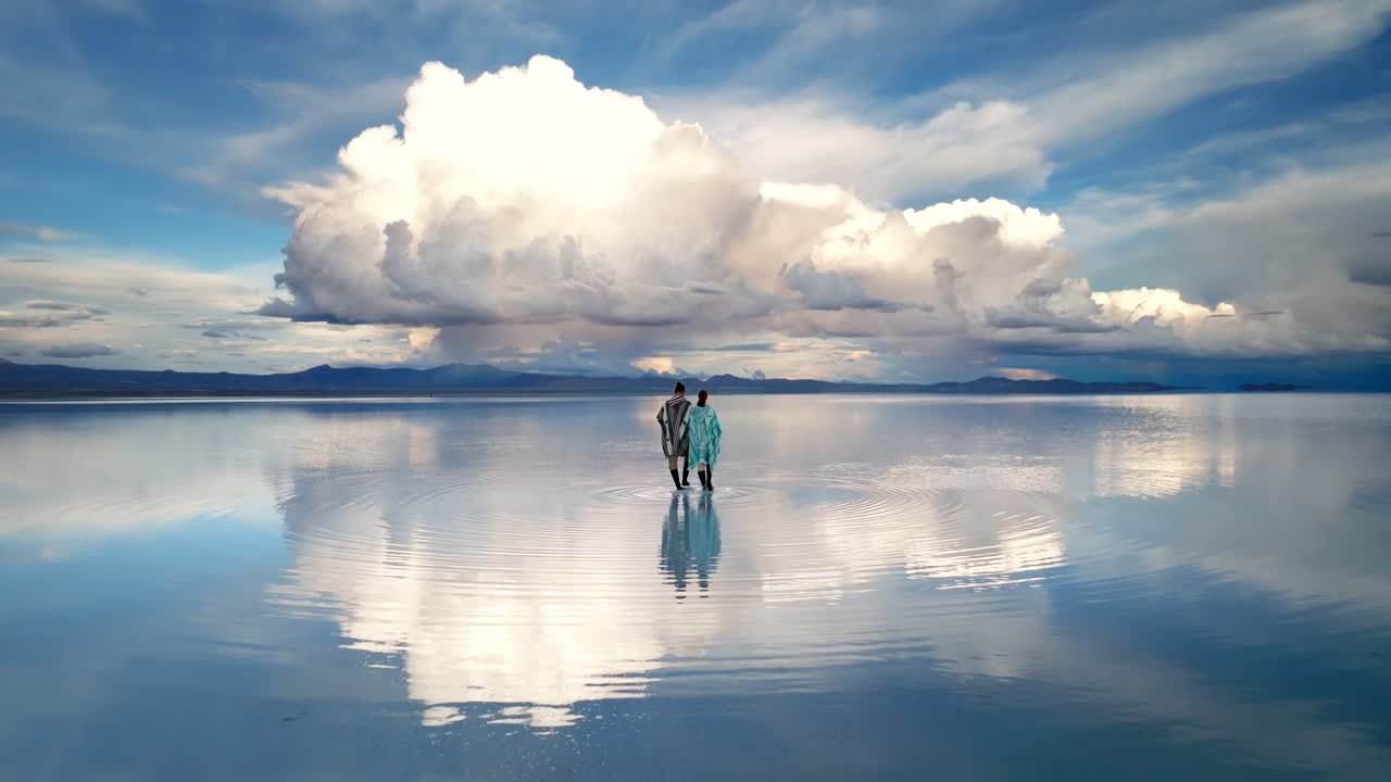 Uyuni salt flat perfect reflection of tourist couple walking in shallow water