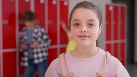 Video-portrait-of-smiling-schoolgirl-standing-in-school-corridor