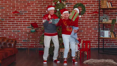 viejos abuelos alegres con la nieta niño bailando en casa cerca del árbol de navidad decorado