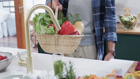 midsection of diverse couple unpacking shopping in kitchen at home, in slow motion