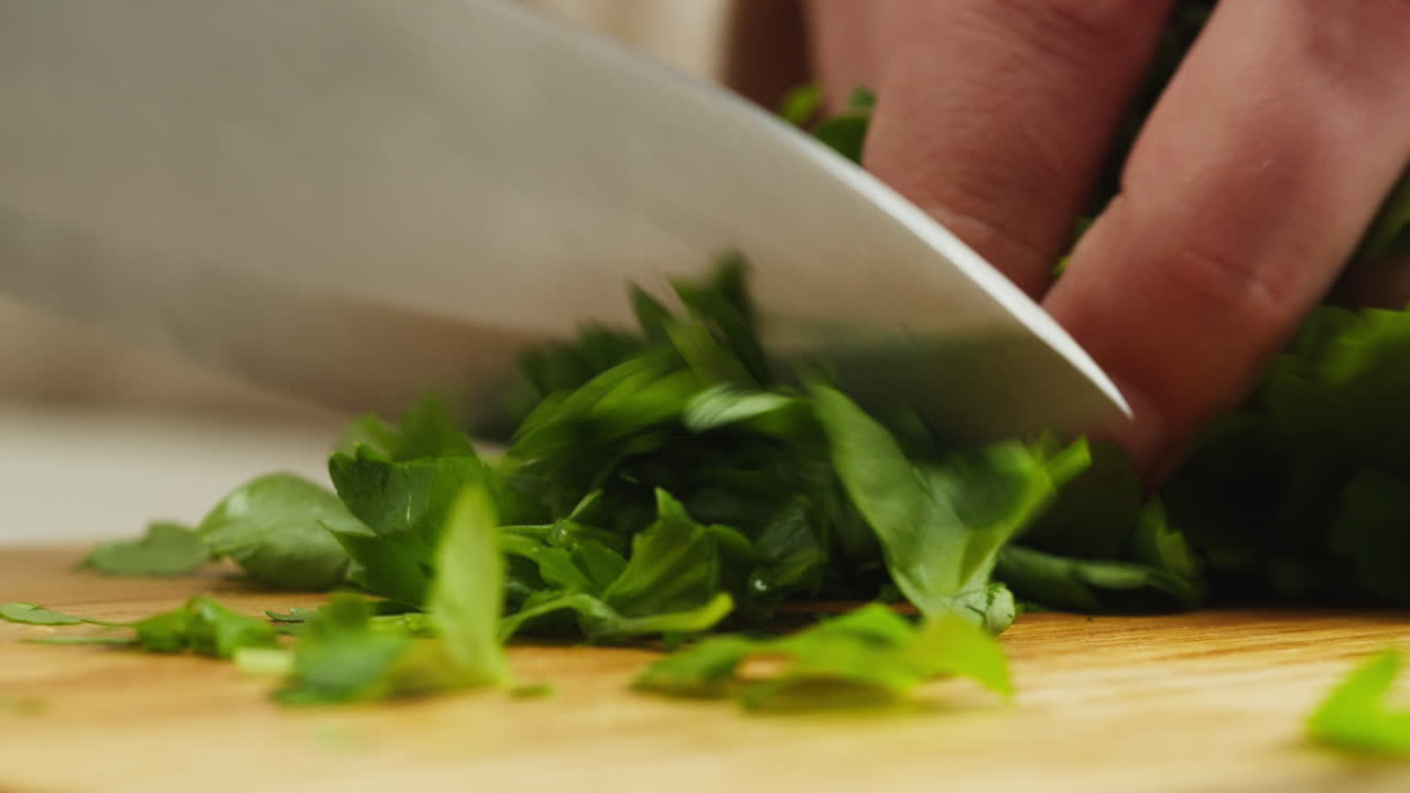 Close-up of Hand Chopping Fresh Green Parsley on a Cutting Board