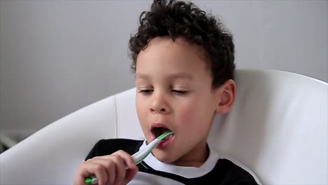 niño cepillándose los dientes con un cepillo de dientes con fondo gris almacen de metraje de video