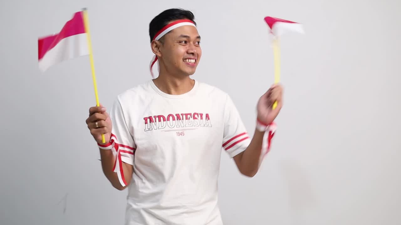 Happy Indonesian man standing holding red white flag to celebrates Indonesia independence day