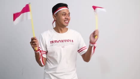 happy indonesian man standing holding red white flag to celebrates indonesia independence day