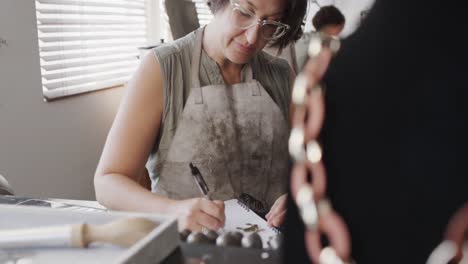 trabajadora caucásica ocupada dibujando el diseño de joyas en un estudio de joyas en cámara lenta