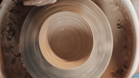 hands shaping clay on a pottery wheel