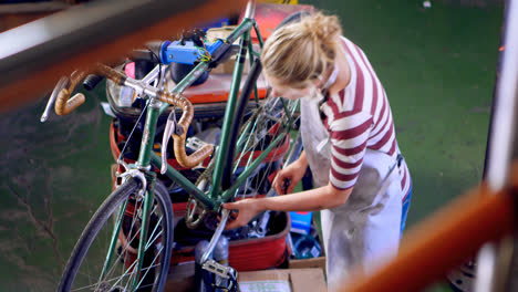 Woman-repairing-cycle-at-workshop-4k