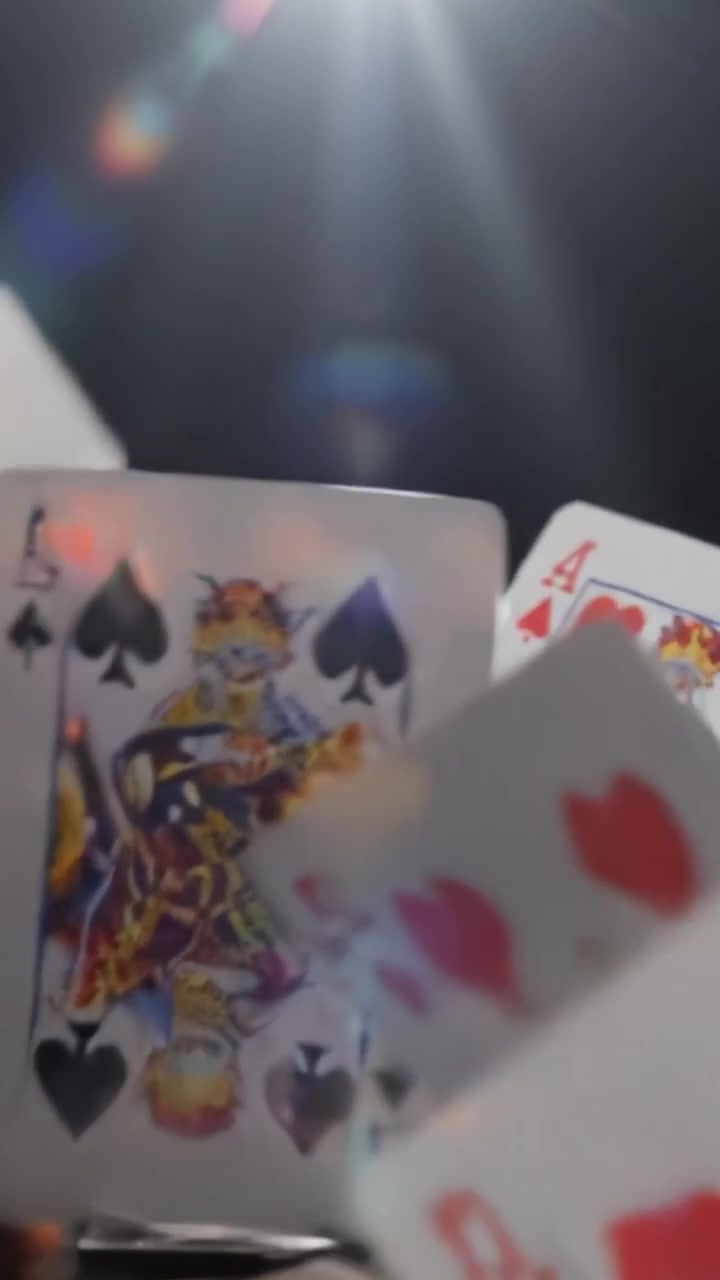 Un'incantevole esposizione di carte da gioco che cadono, catturate in un'illuminazione drammatica, rivelando le complessità dei disegni delle carte e l'attesa del gioco imminente.