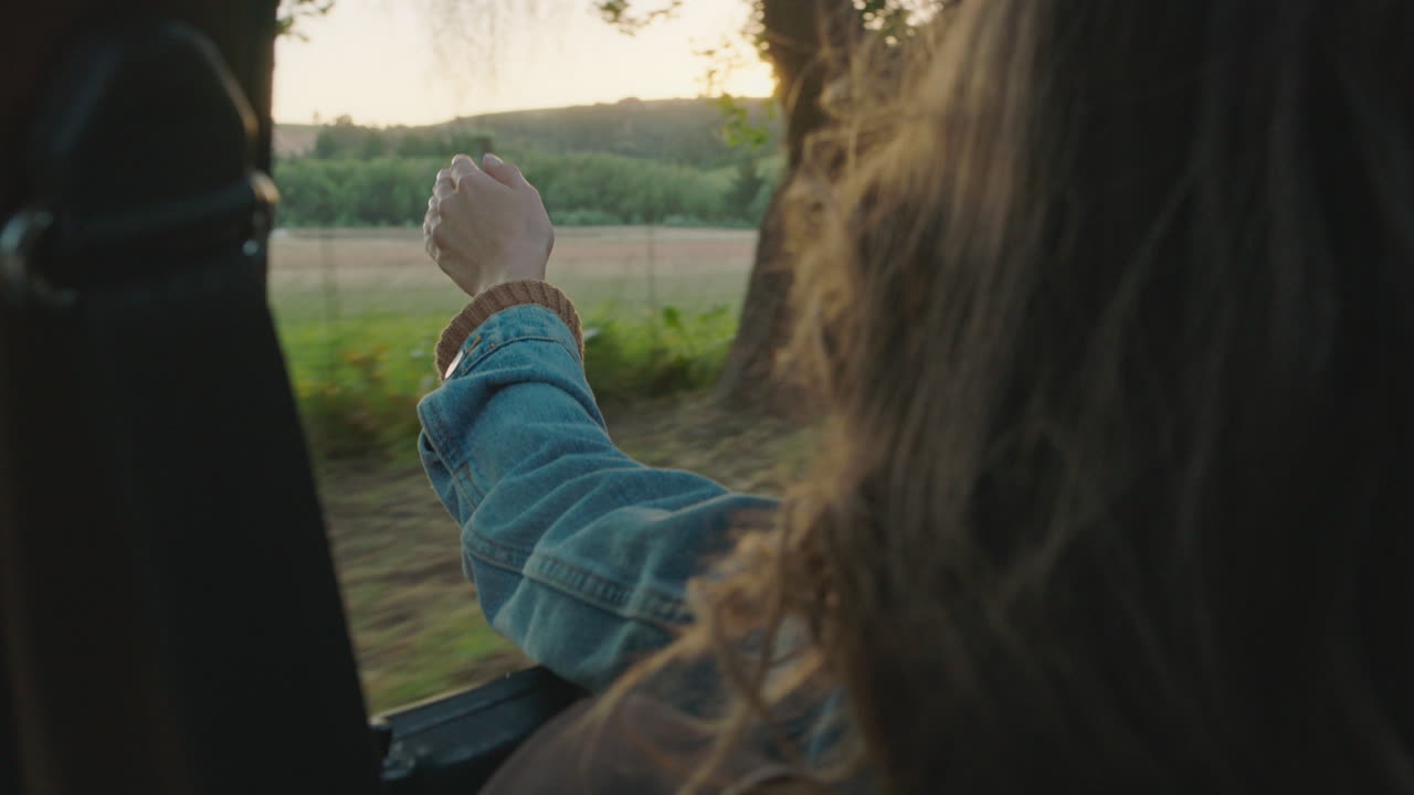 mujer en el coche con la mano afuera de la ventana sintiendo el viento soplando a través de los dedos conduciendo en el campo viajando en vacaciones de verano viaje por carretera disfrutando de la libertad en la carretera al atardecer