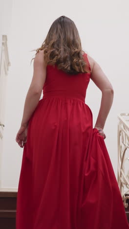 senhora de vestido vermelho sobe as escadas com elegância. jovem mulher volta para o quarto em residência privada depois de festa exclusiva. tom para a noite de glamour