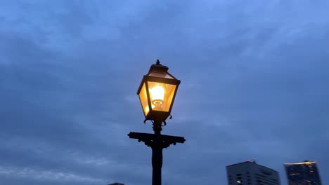 glowing street lamp against twilight sky, city silhouette in background, peaceful evening atmosphere