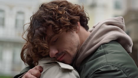 Affectionate-couple-hugging-outside.-Man-putting-head-on-woman-shoulder-outdoor.