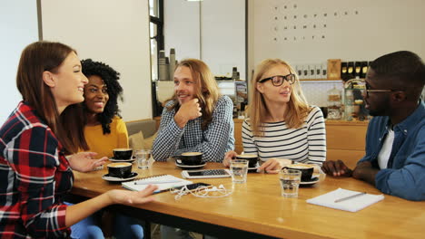 group multiethnic group of friends talking sitting at a table in a cafe