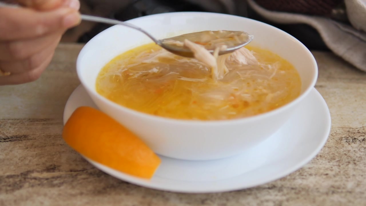 Person spiser hjemmelavet kyllingenudelsuppe fra en skål